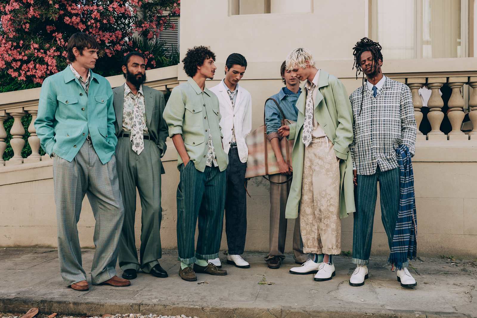 Group of models wearing colourful Paul Smith tailoring in a courtyard.
