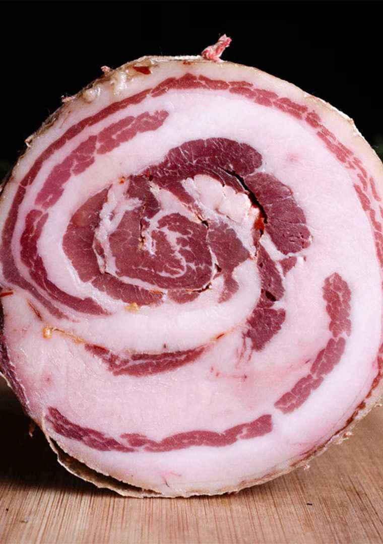 Dettaglio_pancetta_arrotolata_di_maiale_nero_brado_con_strati_di_carne_e_grasso_lavorazione_artigian_ooerny